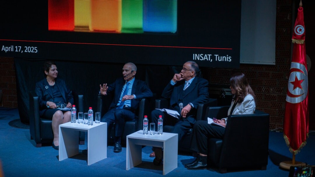 Panel discussion on stage with several speakers and microphones