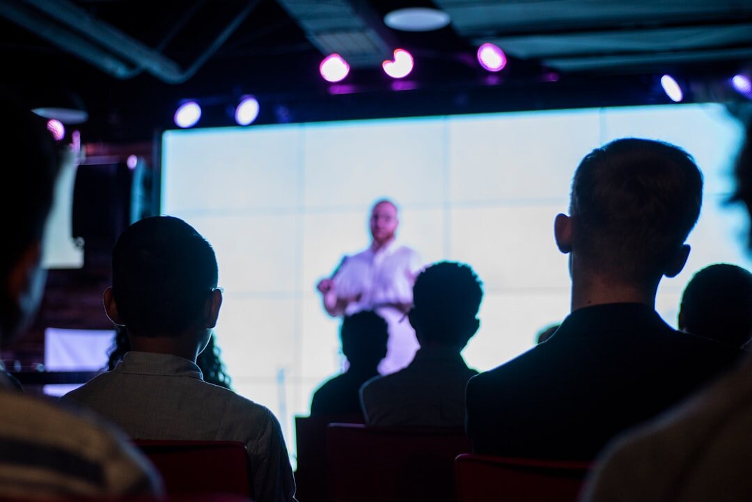 Speaker presenting on stage to a large business audience